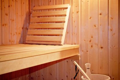 Saunakabine aus hellem Holz mit Glasfront und breiten Liegebänken