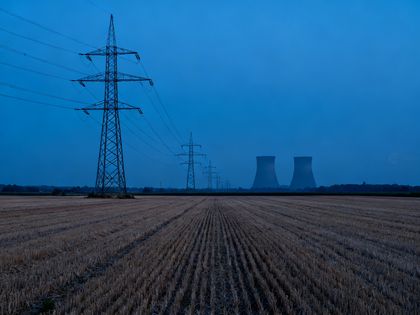 Hochspannungsmasten über einem abgeernteten Feld in der Abenddämmerung